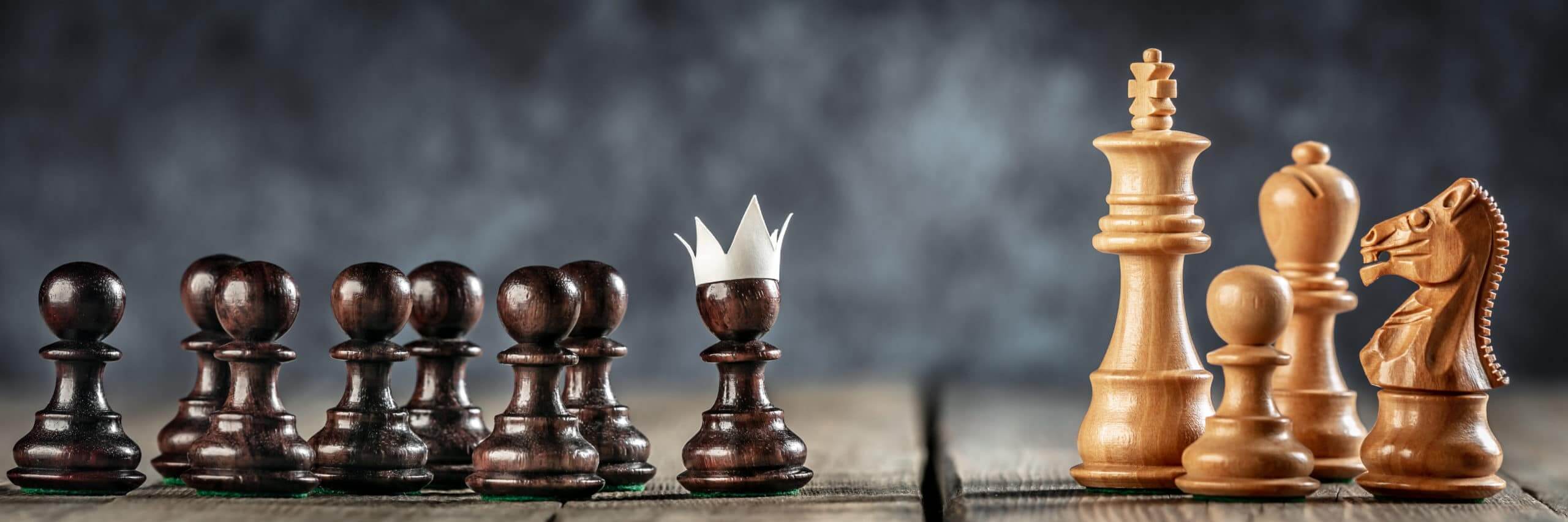 Small Courageous Pawn With Fake Paper Crown Costume Leading Others Into Battle Against The Enemy - Business Entrepreneur / Leadership Concept